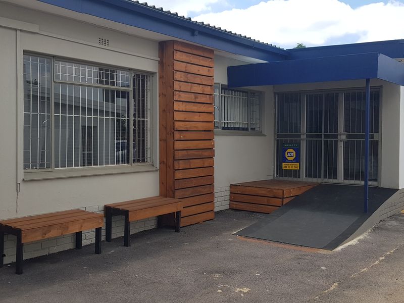 Front entrance of the office building featuring a wheelchair ramp, security gate, and modern timber cladding accents.