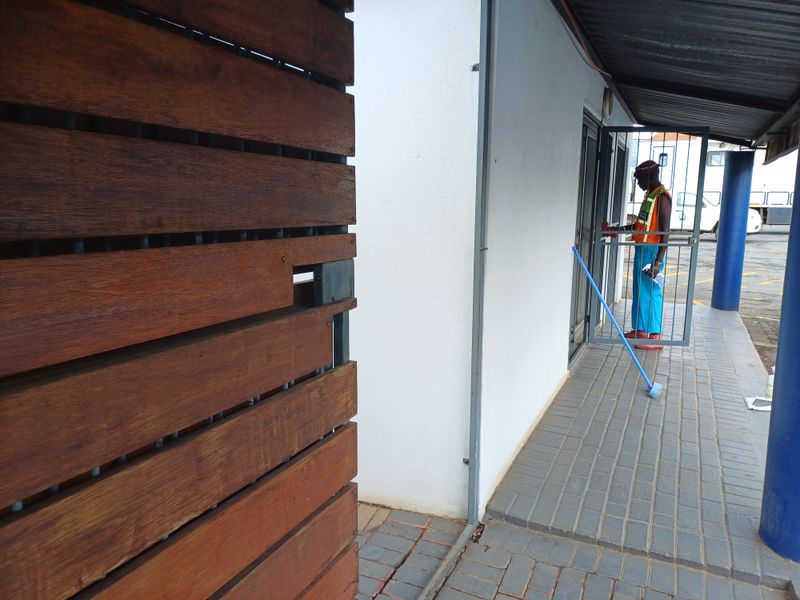 Exterior view of an office entrance featuring a paved walkway, covered access, and a timber privacy screen.