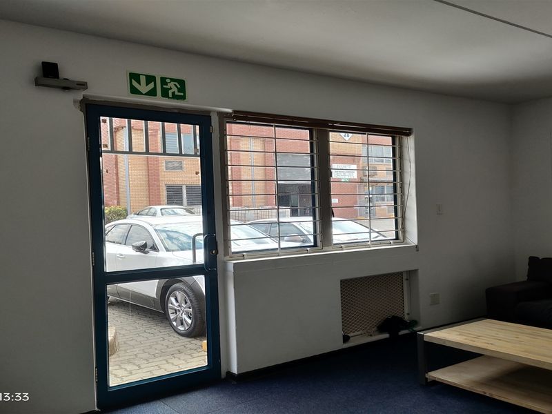 Entrance area featuring a security door, protective window bars, and emergency signage, providing direct access to the exterior parking area.
