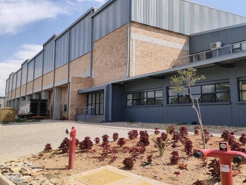 A modern industrial facility featuring a brick and metal facade, paved driveway, and well-maintained landscaping with visible fire hydrant infrastructure.