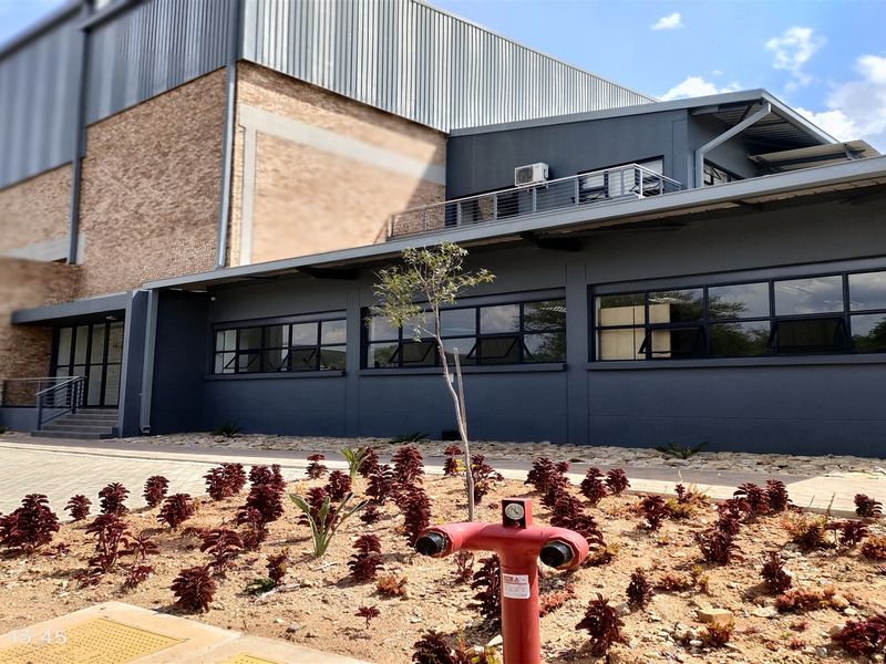 Modern industrial building exterior featuring a combination of brick and dark metal cladding, large windows, and integrated fire safety infrastructure.