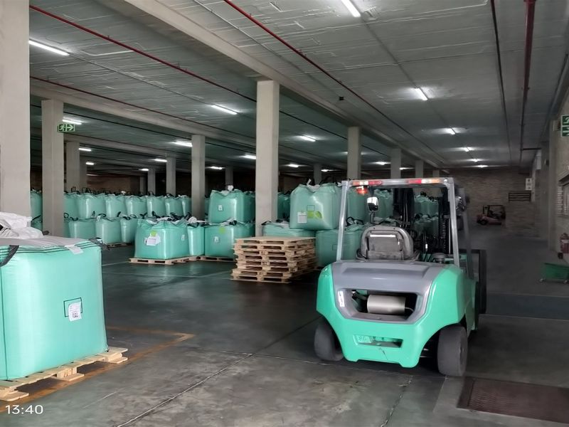 Spacious industrial warehouse area featuring high ceilings, concrete flooring, fire sprinkler systems, and a large roller shutter door for efficient logistics and storage operations.