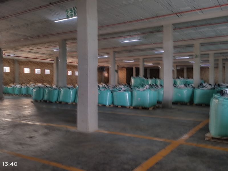 Spacious industrial warehouse area featuring concrete flooring, exposed ceiling with integrated lighting, and structural support columns, currently utilized for bulk storage.