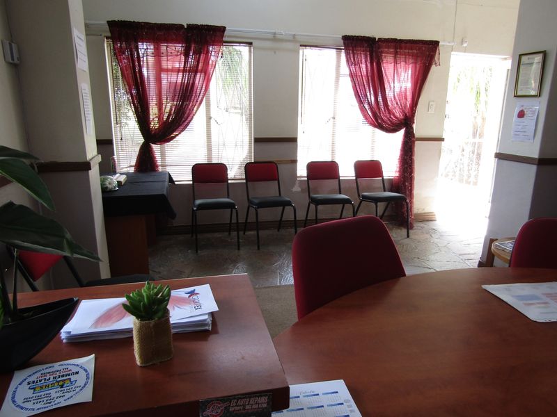 A functional office space featuring stone flooring, security bars on the windows, and fitted blinds, providing a practical work environment.