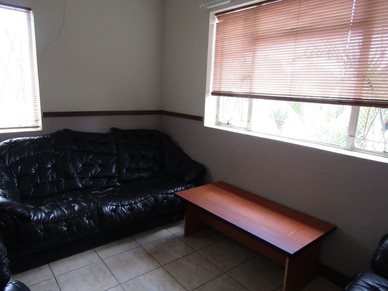 Office space featuring tiled flooring, venetian blinds, and a chair rail, with a visible crack in the wall requiring attention.