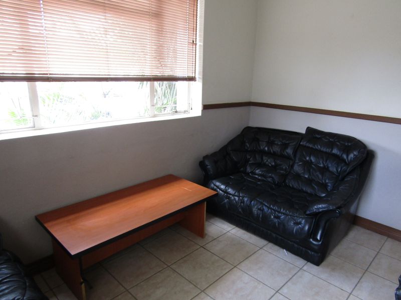 A functional office space featuring tiled flooring, a chair rail, and venetian blinds providing natural light control.
