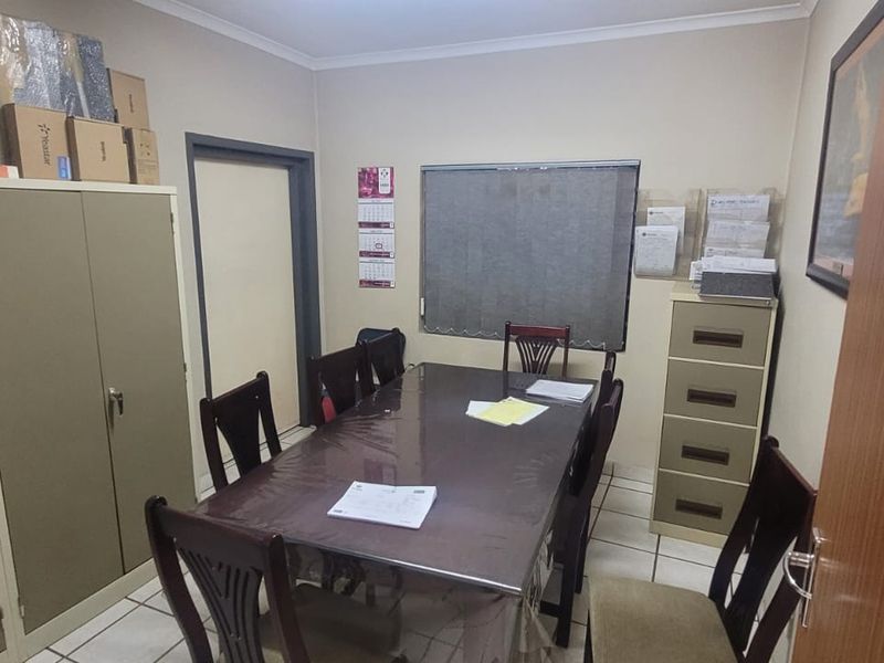 A functional office space featuring tiled flooring and vertical blinds, suitable for a professional work environment within an industrial property.