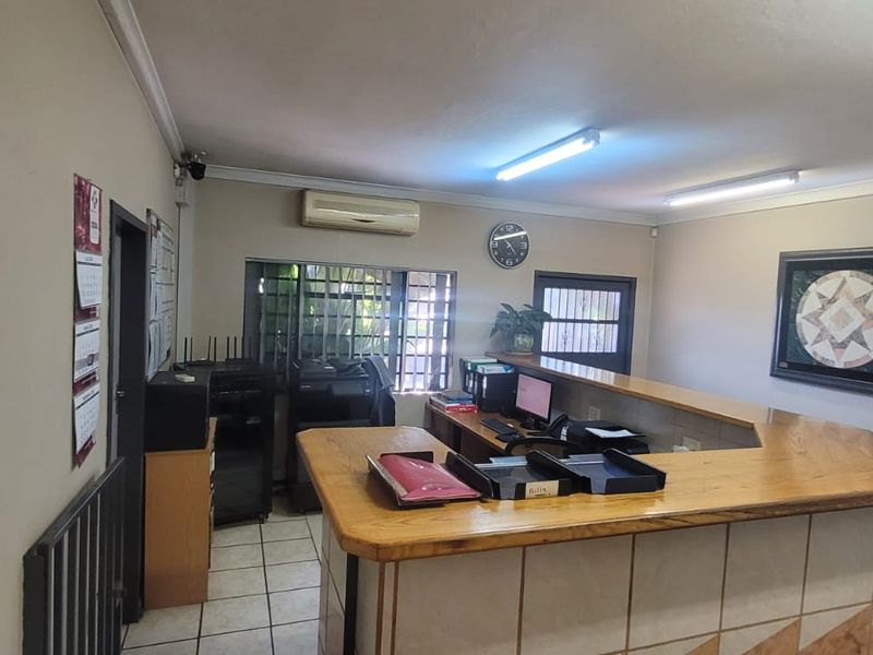 Functional office space featuring a built-in reception desk, tiled flooring, and integrated air conditioning, suitable for administrative or industrial operations.