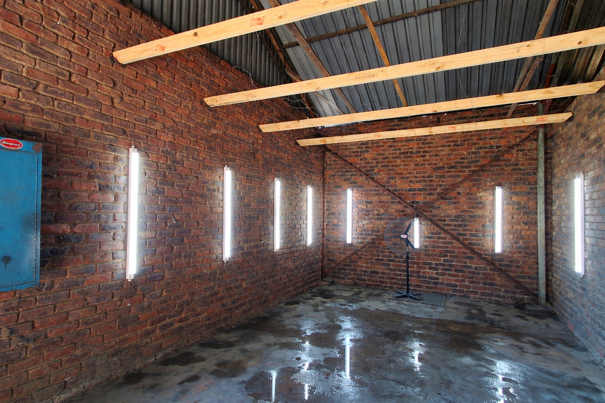 A utilitarian space featuring exposed brick walls, concrete flooring, and industrial-style fluorescent lighting, suitable for a workshop or storage area.