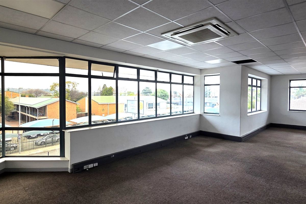 Spacious, empty office suite featuring large windows with natural light, suspended ceilings with integrated air conditioning, and carpeted flooring.