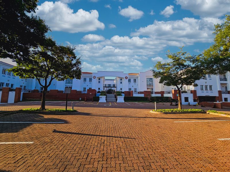 Front view of a professional office complex featuring a paved parking area, brick retaining walls, and a central building entrance.