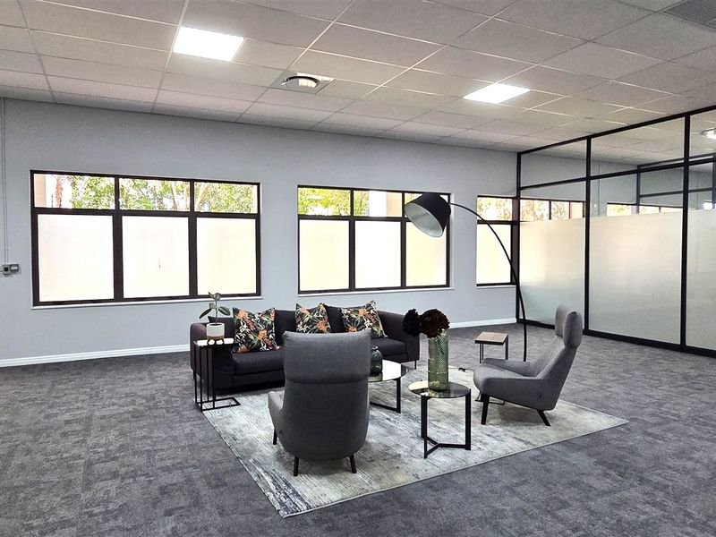 Modern open-plan office space featuring carpet tiles, suspended ceilings with recessed lighting, and glass-partitioned meeting rooms with aluminium frames.