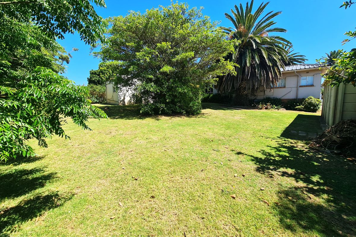 A spacious rear garden area featuring a well-maintained lawn, mature trees, and established perimeter boundaries, offering a private outdoor space.