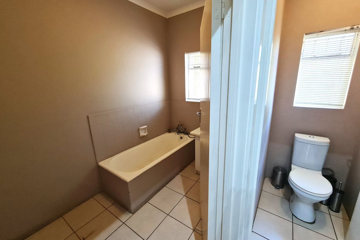 A functional bathroom featuring a built-in bathtub, toilet, and tiled flooring, requiring cosmetic updates to modernize the space.