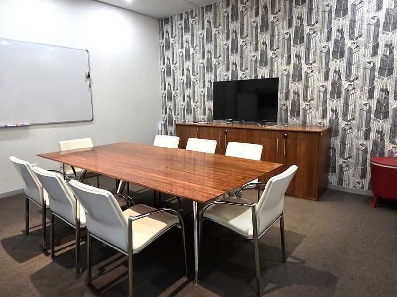 A functional office meeting room featuring a large conference table, wall-mounted whiteboard, and patterned feature wall.