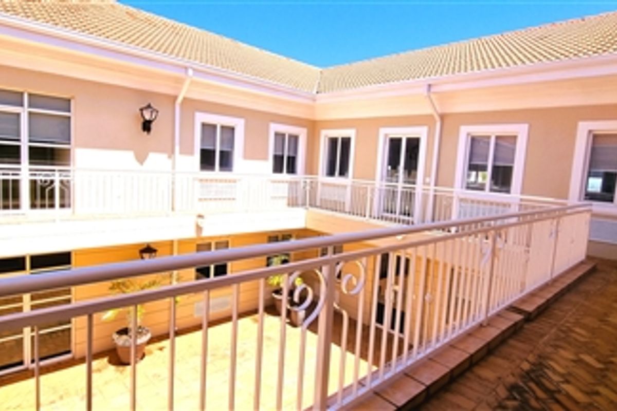 A well-maintained exterior courtyard area featuring a tiled balcony with wrought iron railings, providing access to multiple office suites via sliding glass doors.