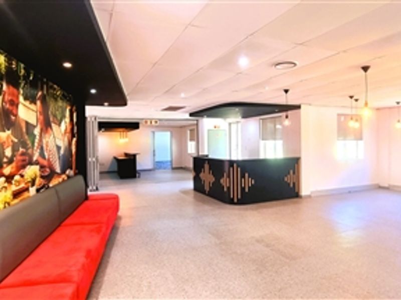 Spacious open-plan office area featuring a built-in service counter, integrated bench seating, suspended ceilings, and modern pendant lighting throughout the workspace.