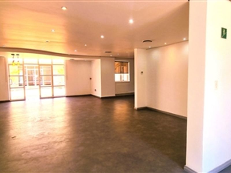 Spacious open-plan office area featuring recessed downlighting, neutral finishes, and glass partition doors leading to an adjacent space.