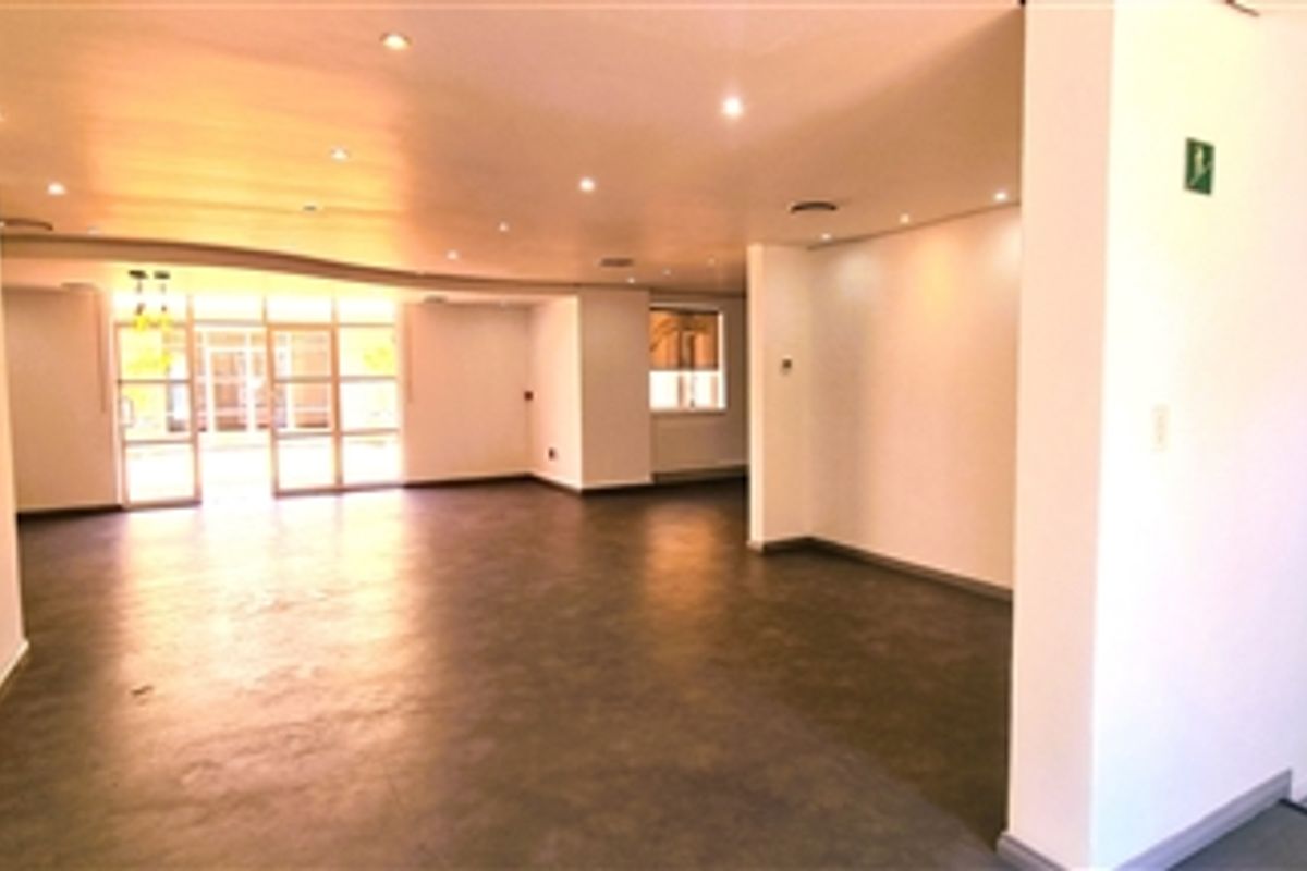 Spacious open-plan office area featuring recessed downlighting, neutral finishes, and glass partition doors leading to an adjacent space.