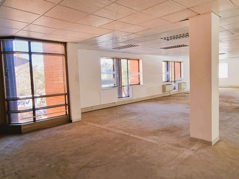 Spacious open-plan office area featuring large windows, structural columns, suspended ceilings, and integrated HVAC units, currently vacant and ready for refurbishment.