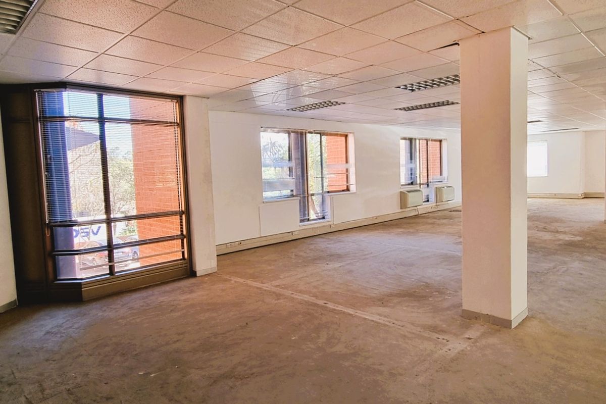Spacious open-plan office area featuring large windows, structural columns, suspended ceilings, and integrated HVAC units, currently vacant and ready for refurbishment.