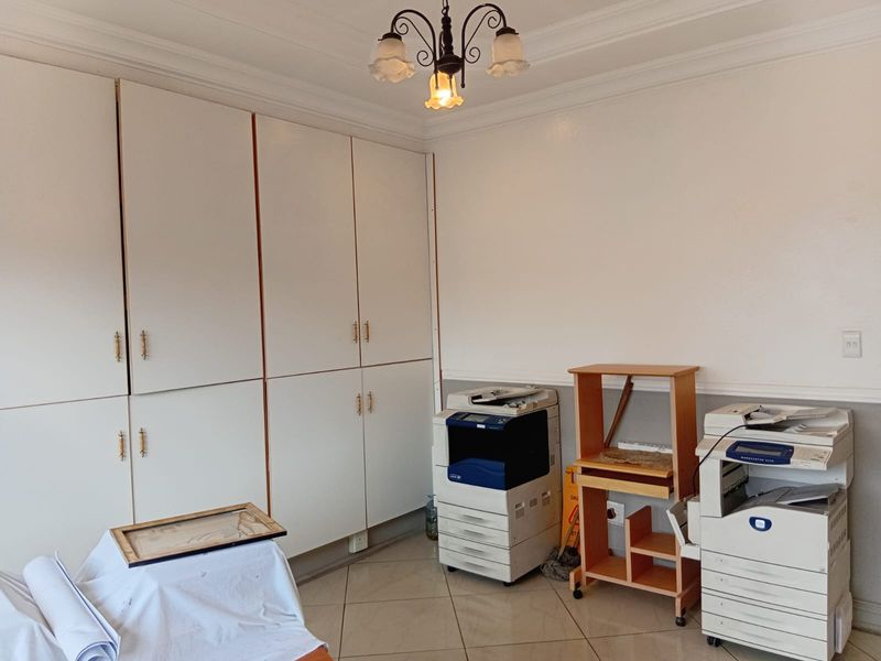 A functional office space featuring extensive built-in floor-to-ceiling cabinetry, tiled flooring, and decorative crown molding.