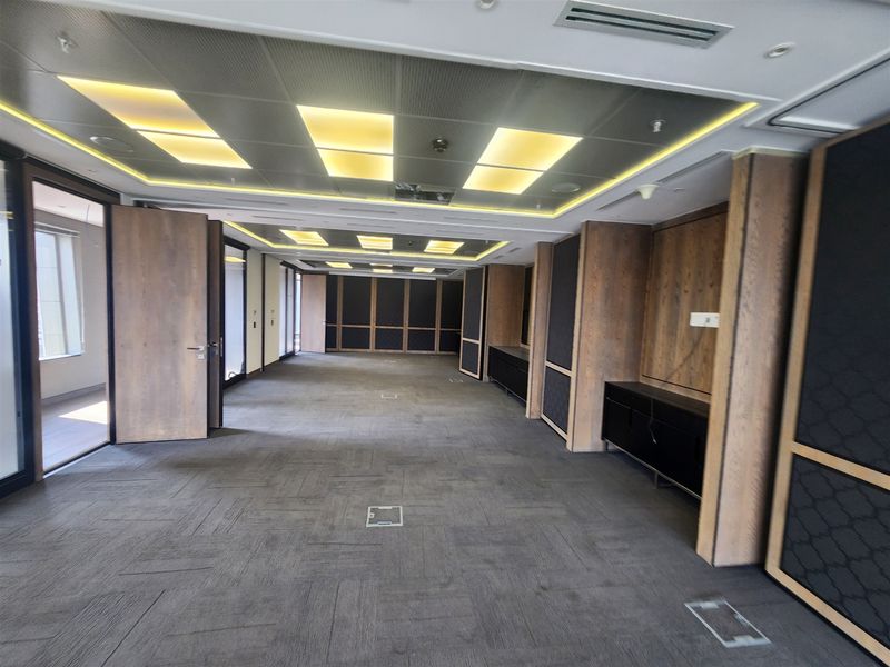 A spacious, modern office area featuring high-quality wood paneling, recessed ceiling lighting, and integrated floor power outlets in a professional, open-plan layout.