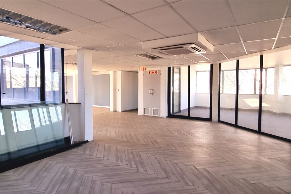 Spacious, modern open-plan office area featuring herringbone tile flooring, suspended ceilings, integrated air conditioning, and extensive floor-to-ceiling glass partitioning for natural light.
