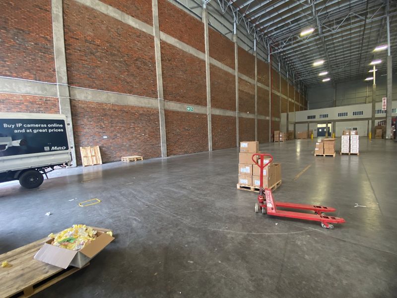 Spacious industrial warehouse unit featuring high ceilings, exposed brick walls, polished concrete floors, and functional overhead lighting, suitable for storage or distribution operations.
