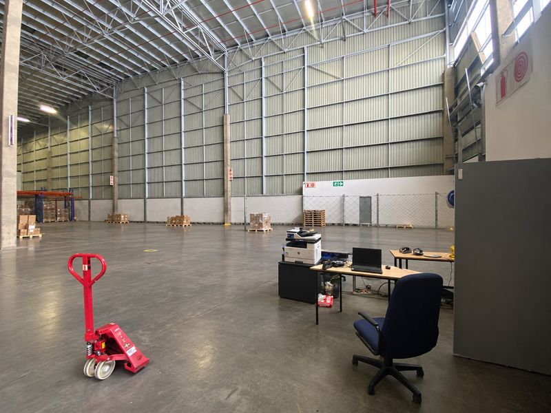 Spacious industrial warehouse featuring high ceilings, durable concrete flooring, and exposed steel structural elements, suitable for logistics or manufacturing operations.