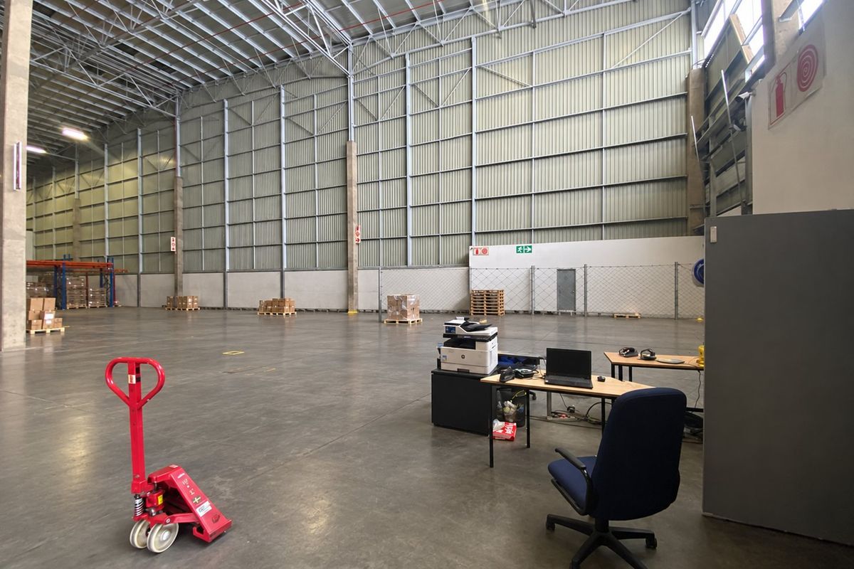 Spacious industrial warehouse featuring high ceilings, durable concrete flooring, and exposed steel structural elements, suitable for logistics or manufacturing operations.