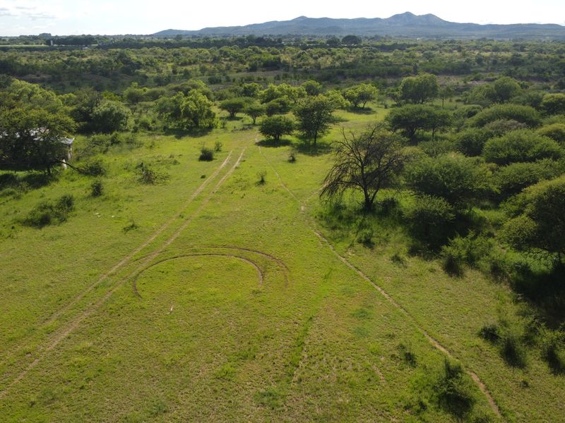 An aerial view of a large, undeveloped commercial land parcel featuring native vegetation and existing dirt access tracks.