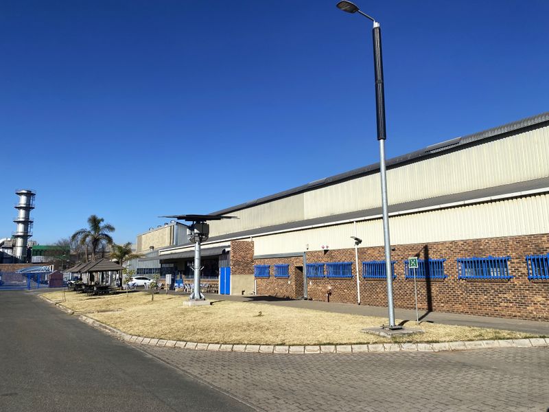 Exterior view of an industrial facility featuring a combination of face brick and corrugated metal cladding with secure window bars and paved access.