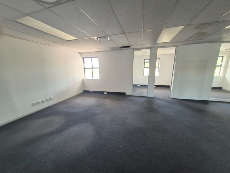 An empty, open-plan office space featuring carpeted flooring, a suspended ceiling with recessed lighting, and glass partitioning, ready for custom fit-out.