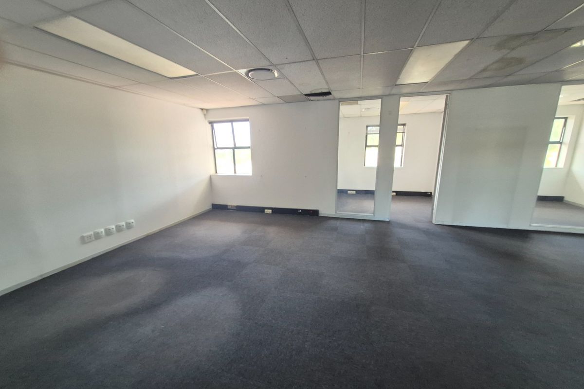 An empty, open-plan office space featuring carpeted flooring, a suspended ceiling with recessed lighting, and glass partitioning, ready for custom fit-out.