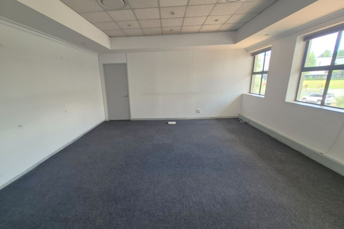 A spacious, empty office suite featuring a suspended ceiling, recessed lighting, and large windows providing natural light, ready for custom fit-out.