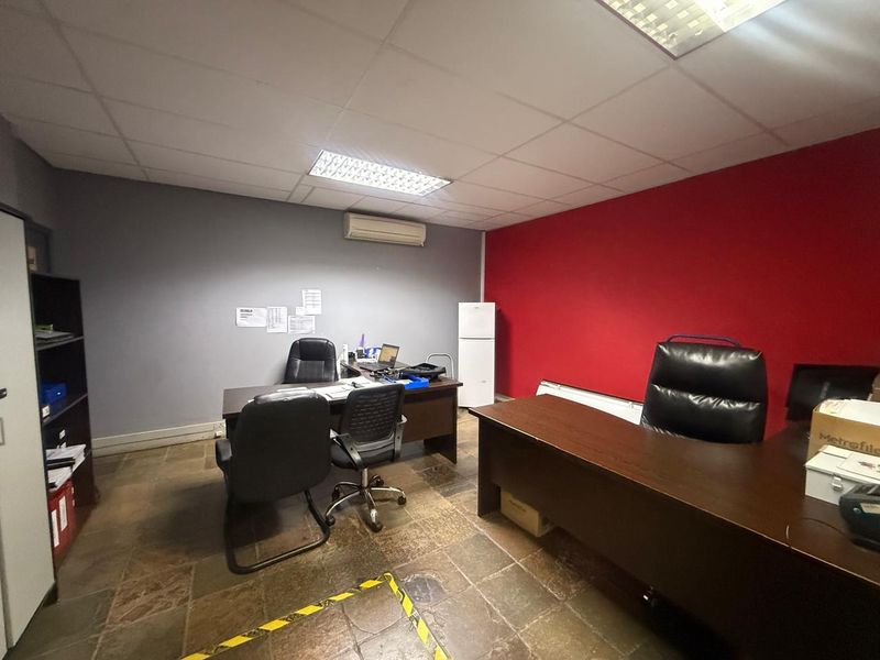 Functional office space featuring tiled flooring, recessed ceiling lighting, and a wall-mounted air conditioning unit.