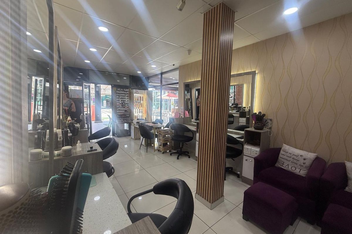 A well-lit retail salon space featuring tiled flooring, recessed ceiling lighting, and multiple built-in styling stations with integrated mirrors.