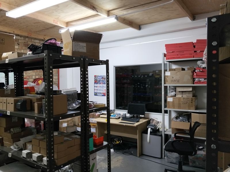 Industrial utility or storage space featuring exposed timber ceiling joists, brickwork walls, and an internal window looking into an adjacent area.