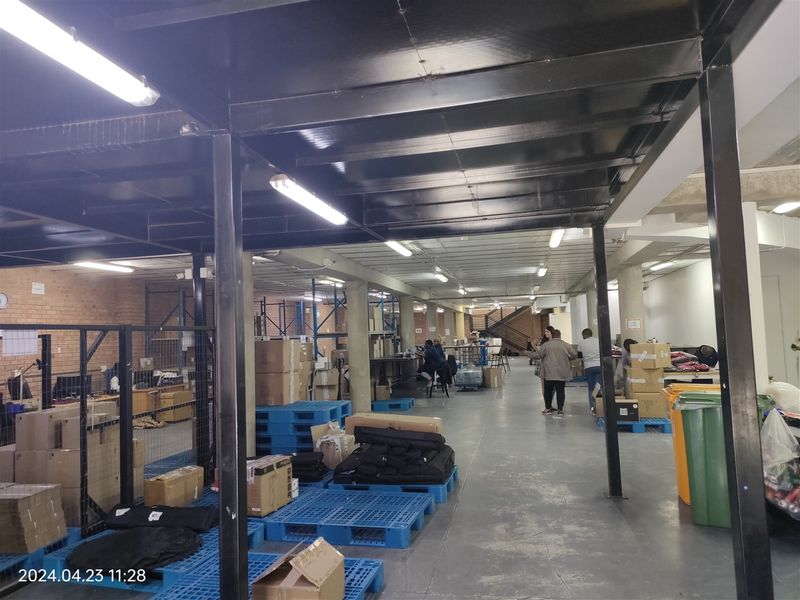 Spacious industrial utility area featuring exposed steel beams, concrete flooring, and overhead fluorescent lighting, suitable for warehouse or storage operations.