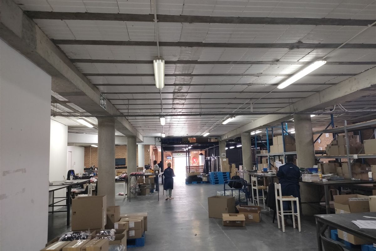 Spacious industrial utility area featuring exposed concrete ceilings, support columns, and functional fluorescent lighting, suitable for warehouse or workshop operations.