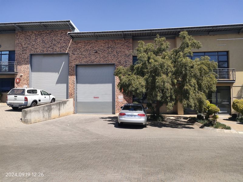 Front elevation of an industrial unit featuring dual roller shutter doors, a loading ramp, and paved access area.