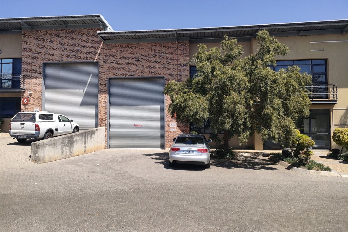 Front elevation of an industrial unit featuring dual roller shutter doors, a loading ramp, and paved access area.