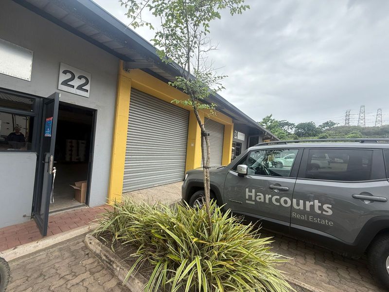 Exterior view of an industrial unit featuring a roller shutter door, pedestrian entrance, and paved frontage.