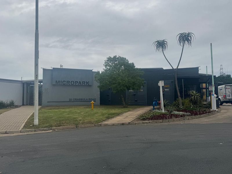 Front view of Micropark industrial facility featuring paved walkways, landscaped garden, signage, and secure gated entrance.