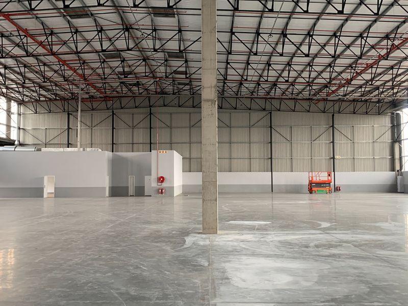 Spacious industrial warehouse featuring high ceilings with exposed steel trusses, polished concrete floors, and integrated fire safety systems.