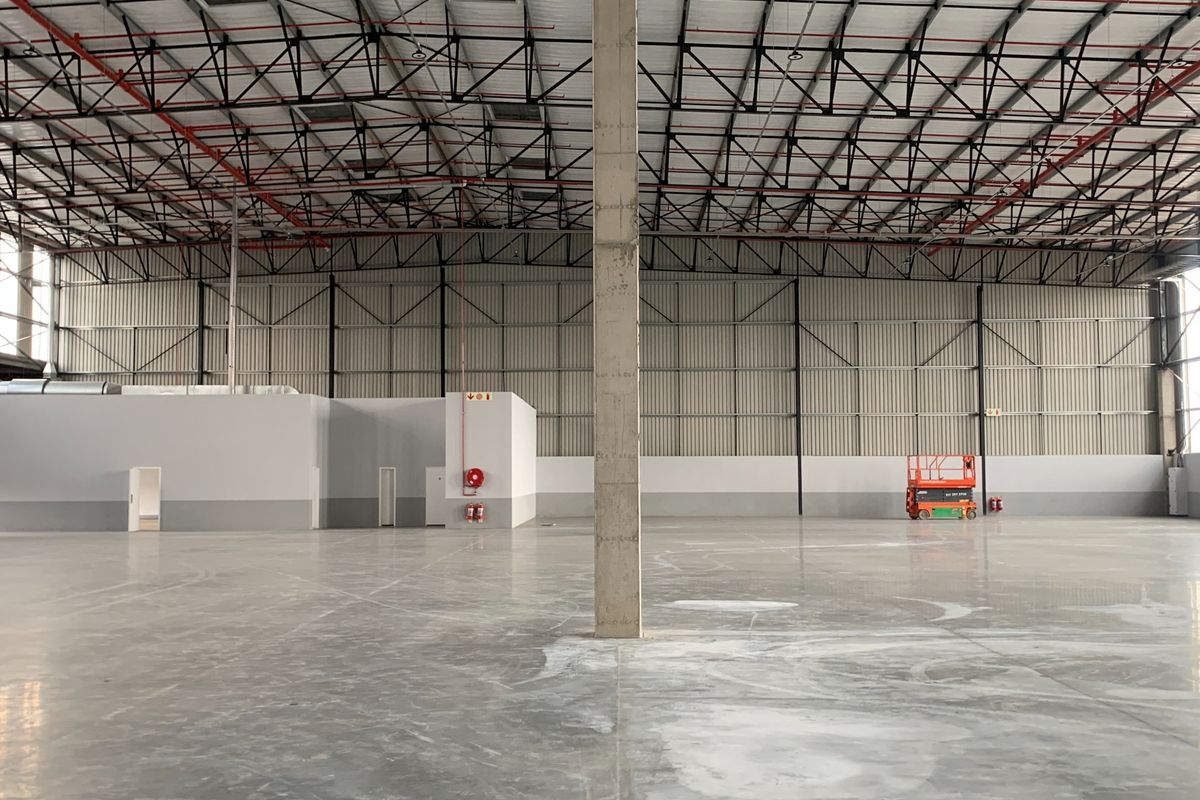 Spacious industrial warehouse featuring high ceilings with exposed steel trusses, polished concrete floors, and integrated fire safety systems.