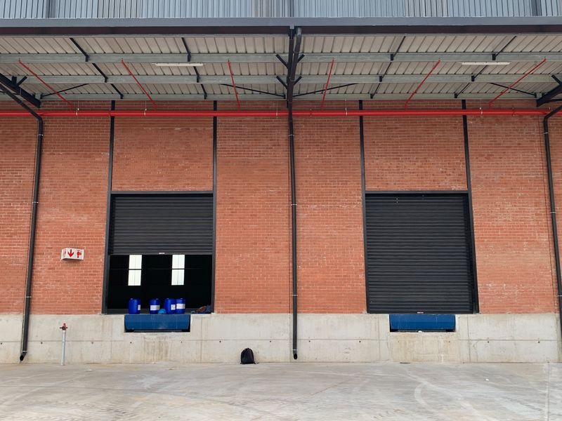 Industrial loading bay area featuring two roller shutter doors, concrete loading docks, and exposed brick facade with integrated fire safety infrastructure.