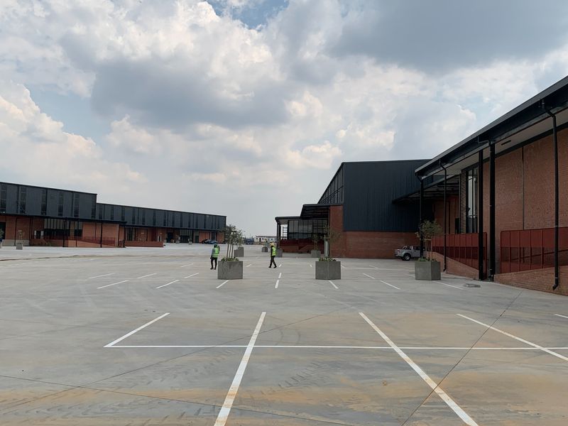 Spacious industrial yard featuring concrete paving, marked parking bays, and modern brick and metal-clad warehouse structures.