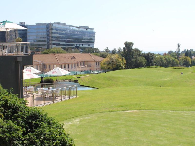 Elevated view overlooking a manicured golf course, water feature, and surrounding office park infrastructure.